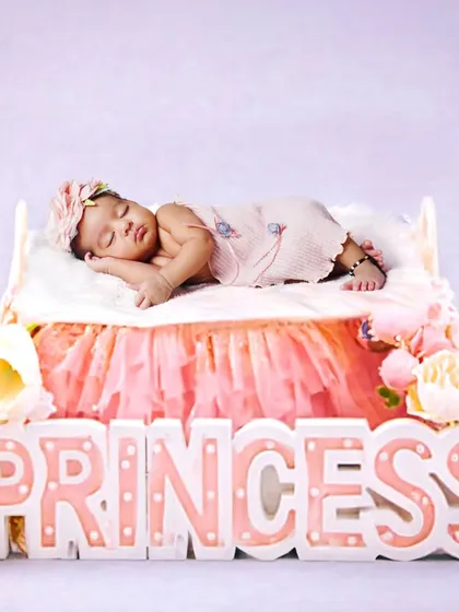 A sweet newborn princess theme, with the baby sleeping peacefully on a tiny bed. The 'Princess' marquee light adds a lovely touch to this delicate setup.