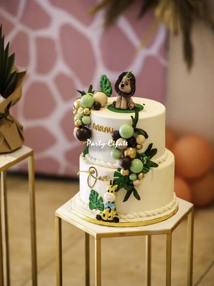 This two-tiered cake perfectly captures the boho-safari theme with its clean white fondant, delicate greenery, and cute, handcrafted animal toppers.