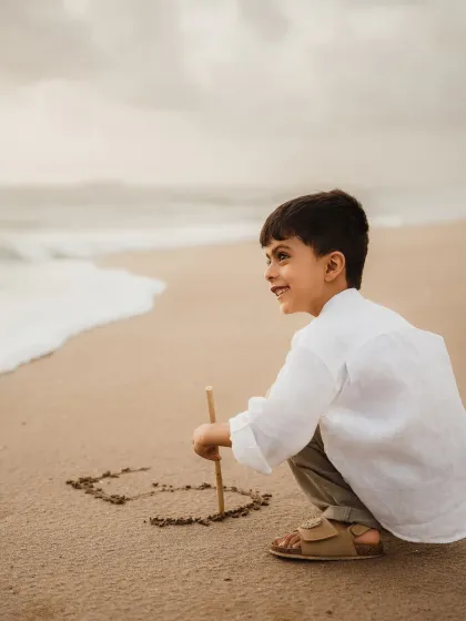 A young boy draws the number five in the sand to celebrate his birthday. This is a creative and personal shot from his outdoor milestone photoshoot.