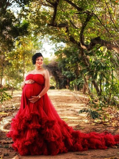 A beautiful walking shot shows how my gowns move. The long train of this red ruffled dress trails behind, creating a sense of movement and elegance in this outdoor maternity photo.
