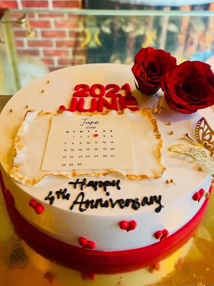 An anniversary cake designed with a calendar page to commemorate the special date, adorned with red roses.
