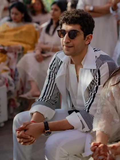 A cool and contemporary look for a daytime wedding event. The brother of the bride wears a stylish black and white striped shirt with white trousers, showing how modern pieces can be incorporated into wedding fashion.