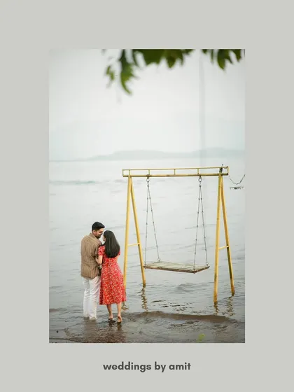 An artistic and minimalist shot of a couple standing by a swing in the water, framed by a single leaf.