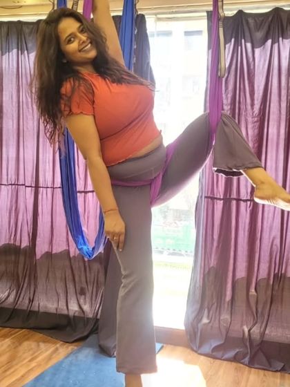 A student smiling while holding a pose in the hammock. This is the joy of movement we cultivate in every class at our Marol studio.