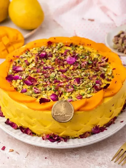 The AamRasmalai cake, garnished with mango slices, crushed pistachios, and dried rose petals. It's a feast for the eyes and the palate.