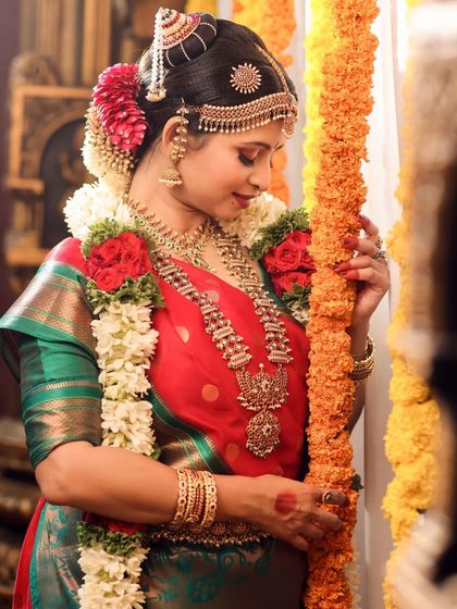 The bride stands beside a string of marigolds, a common element in South Indian weddings, adding a pop of color and festive feel.