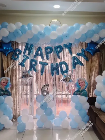 A Frozen themed birthday decoration for a home celebration, with a "Happy Birthday" foil balloon banner and character cutouts.