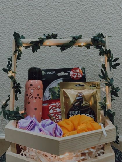 A clear, front-facing view of the popular hexagon hamper, showing the arrangement of the skincare product, deodorant, chocolates, and scrunchies.