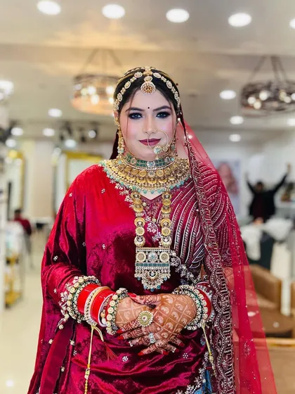 A confident pose from the bride, showing off her complete look. The rich velvet and intricate embroidery of her outfit are complemented by her flawless makeup.