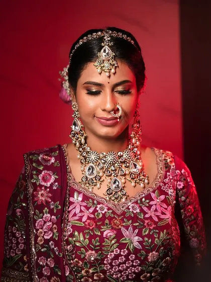 A close-up of the bride's makeup, featuring a soft smokey eye and a hint of shimmer, perfectly complementing her floral embroidered lehenga.