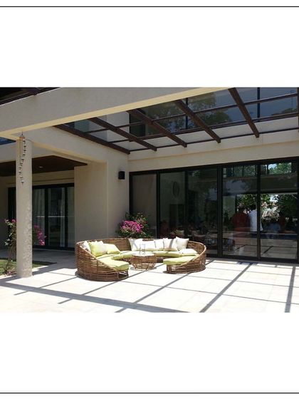A beautifully contrived home in Khandala. This image shows the outdoor lounge area, where comfortable wicker furniture sits under a pergola, blending the interiors with the natural surroundings.
