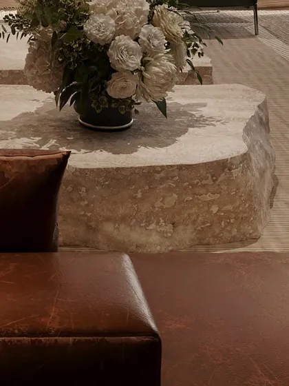 A detail shot of the raw, stone coffee table, which provides a beautiful contrast to the soft leather sofa. This interplay of textures is central to my design philosophy.