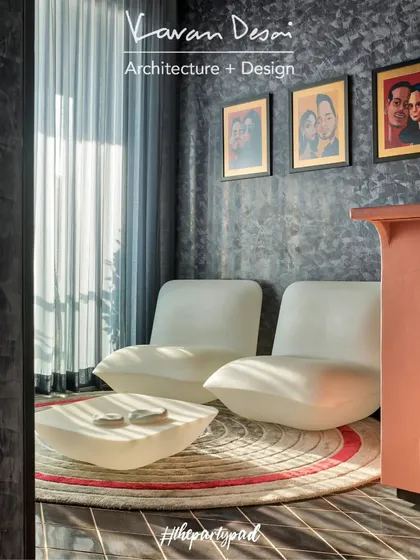 A cozy corner of the Party Pad, featuring modern white lounge chairs and a custom art piece. The dark, textured walls create a moody and sophisticated backdrop for the vibrant furniture and art.