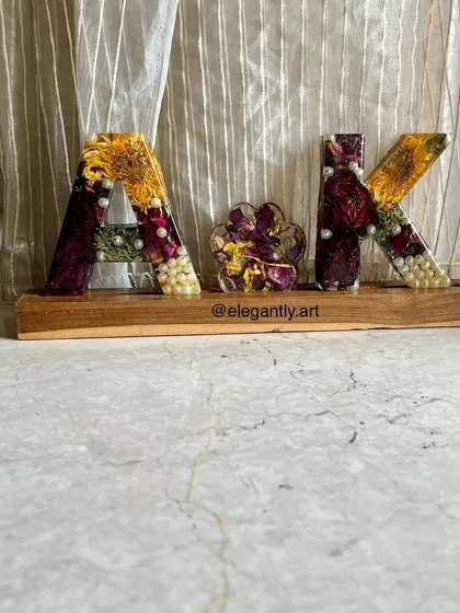 This monogram lamp, spelling out "AK," was made using varmala flowers. The preserved flowers are beautifully suspended in the resin letters, creating a personalized and meaningful piece of decor.
