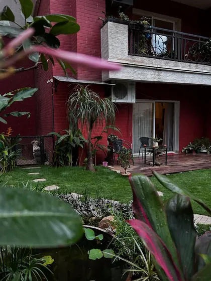 This is the kind of peaceful escape I aim to create. A view across a finished backyard, featuring a rich green lawn, a wooden deck for seating, a small water feature, and a variety of tropical plants that provide privacy and a sense of being surrounded by nature.