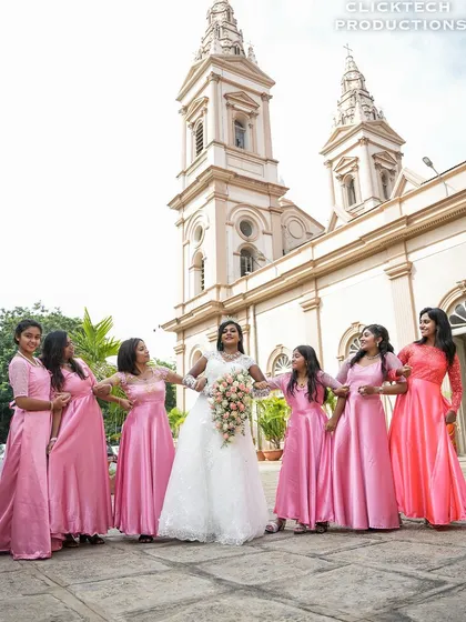 The bride and her bridesmaids hold hands, creating a beautiful and symmetrical shot that celebrates friendship on the wedding day.
