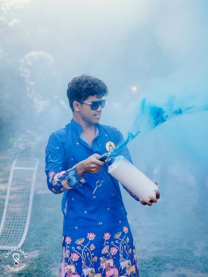 A guest sets off a blue color smoke bomb, adding to the fun and festive atmosphere of the Haldi event.