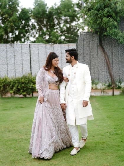 A couple takes a romantic walk through a garden, dressed in exquisite traditional Indian clothing. This image combines the beauty of nature with the elegance of their attire.