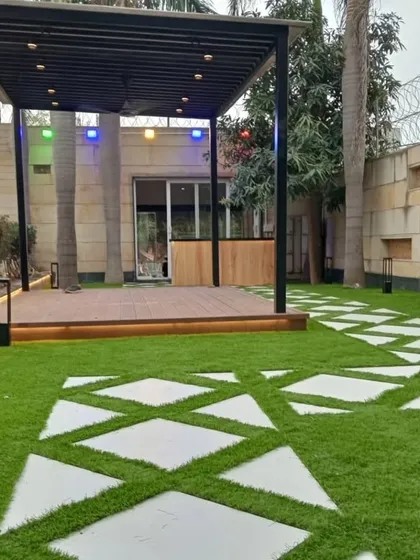 The Dwarka project with pathway lights illuminated, guiding the way to the pergola and bar.