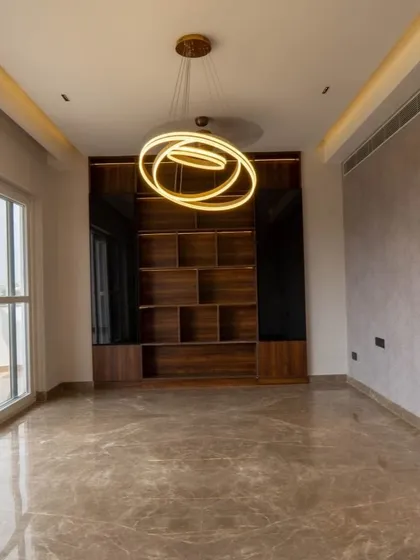 A stunning, modern chandelier acts as a piece of art in this room. The custom-built wooden shelving unit provides a beautiful backdrop, perfect for displaying books and decor.