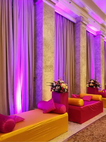 We used vibrant yellow and pink fabrics for this low seating arrangement, perfect for a lively Haldi or Mehendi ceremony, with dramatic purple uplighting.
