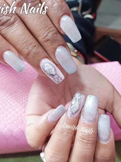 Icy white glitter nails with an elegant silver swirl accent design on long coffin-shaped extensions.