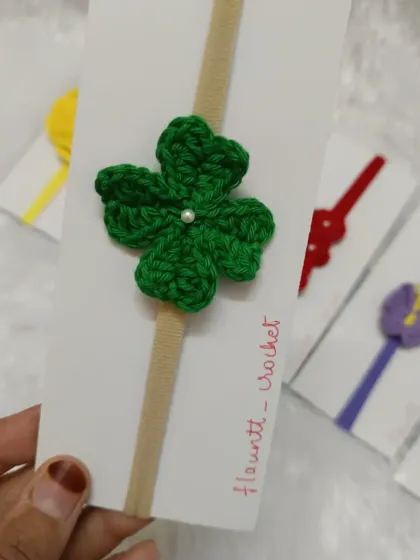 A lucky four-leaf clover headband in a vibrant green. The small pearl in the center adds a touch of elegance to this charming design.
