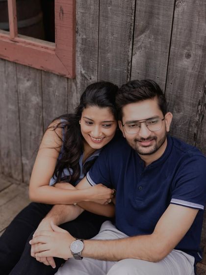 A cozy and relaxed moment against a rustic wooden wall. This candid shot captures the easy comfort and affection of a couple simply enjoying being together.