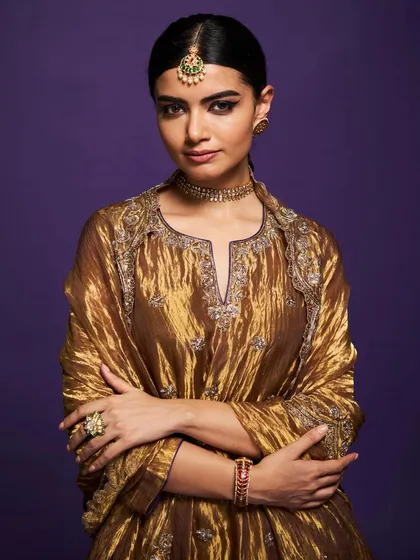 A model exudes regal charm in this crushed metallic gold sharara set, a perfect example of how earthy tones can be incredibly glamorous.