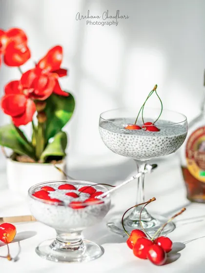 A bright, naturally lit photo of a healthy cherry chia seed pudding. The strong shadows from the golden hour sun add a beautiful, artistic quality to the image.
