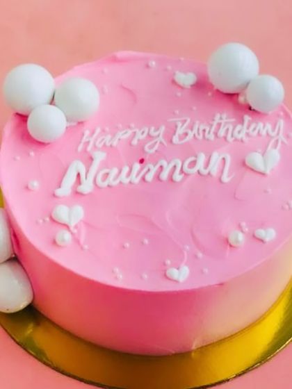 A pretty pink birthday cake decorated with white chocolate spheres and tiny hearts. A sweet and simple design for any celebration.