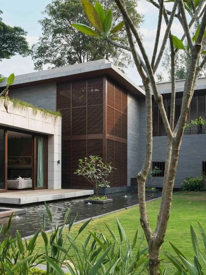 The home is surrounded by a tranquil garden and water features, with large wooden screens providing privacy and filtering sunlight.