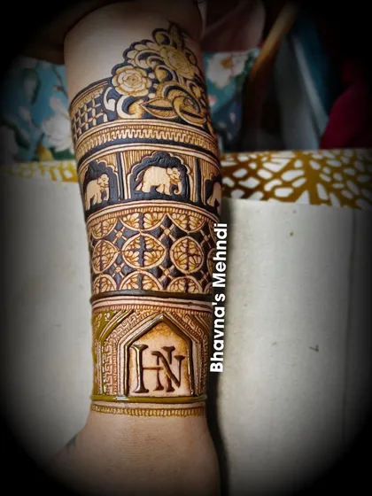 A close up of a beautiful arm band design. This piece features elephants, geometric patterns, and the couple's initials 'HN'.