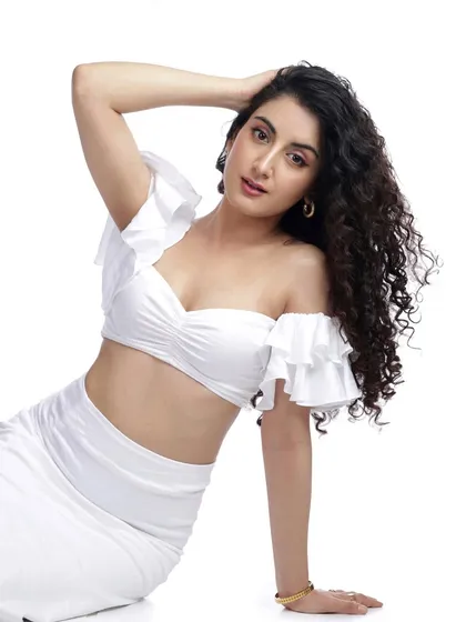 A dynamic pose with the model's arm raised, showcasing her curly hair and the texture of the white outfit.