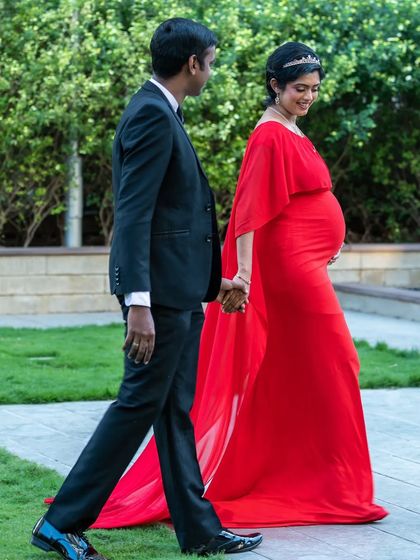 This walking shot showcases the beautiful movement of the red A-line gown and its attached cape. It's a simple yet stunning look for a romantic maternity photoshoot.