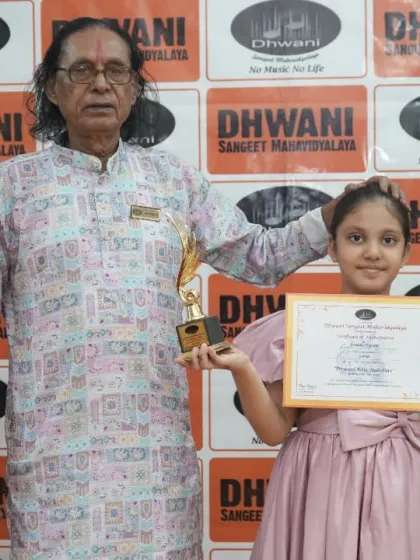 A senior guru with a young student and her trophy.