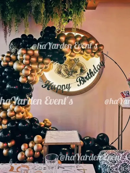 A half-ring balloon garland in black and gold, mounted on a custom circular wooden sign.
