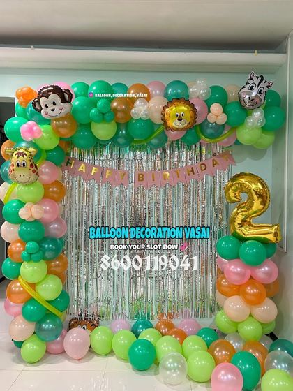 A jungle-themed balloon arch for a 2nd birthday. This decoration uses a silver shimmer curtain and animal-print foil balloons for a playful look.