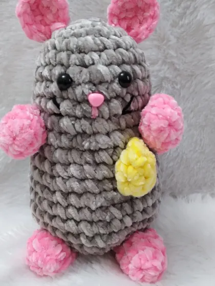 A close-up of a single crochet rat, showing its sweet expression and the texture of the plush yarn.
