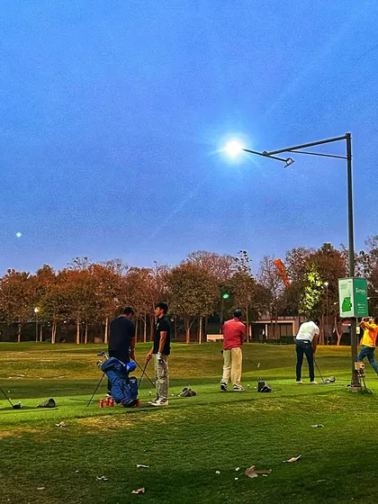 The range under the lights on a clear night, with a group of golfers enjoying an evening session.