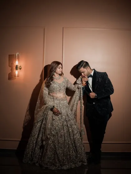 A romantic moment between the couple at their reception. The groom kisses her hand, and her glamorous makeup looks absolutely perfect.