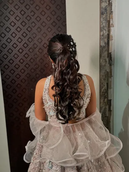 The details of the sangeet ponytail, showing the placement of the sparkling accessories and the texture of the curls.