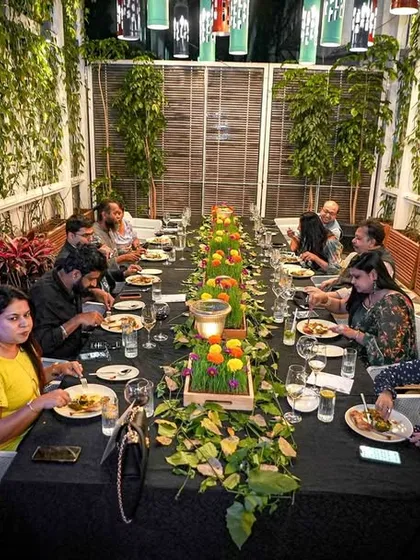 The beautifully set long table at our 'Forgotten Greens' event, decorated with fresh greens and lanterns, creating an intimate and thematic dining experience.