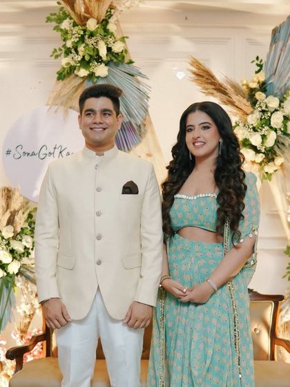 Capturing the happy couple against our custom backdrop. This Roka setup features a boho-chic design with pampas grass, dried palms, and fresh white roses, personalized with the hashtag #SonaGotKampani.