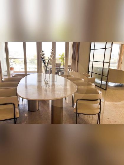 An elegant dining setup with a marble-topped table and minimalist chairs. The space is open and bright, overlooking a balcony and connecting seamlessly with the living area.