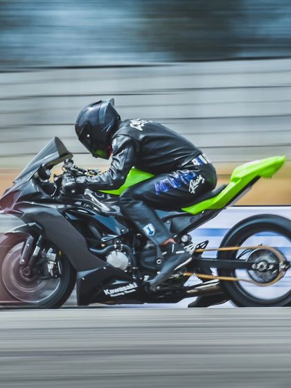 A close-up panning shot of the Kawasaki Ninja drag bike. The rider's focused form and the bike's modifications highlight the serious, competitive nature of our races.
