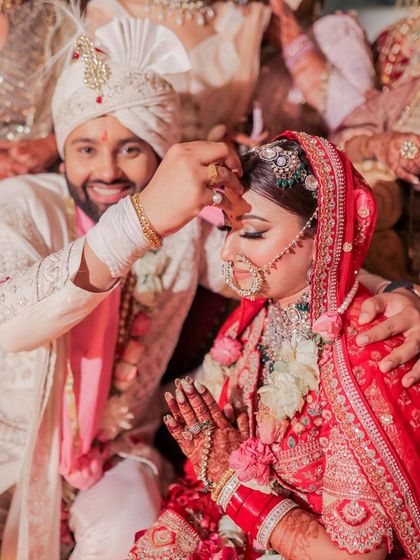 The groom applies sindoor in a sacred and emotional ritual. This close-up shot focuses on the tradition and the deep connection between the couple at a pivotal moment of the wedding.