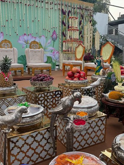 A detailed view of an offering table with pineapple fruit art, silver bird props, and traditional dolls.