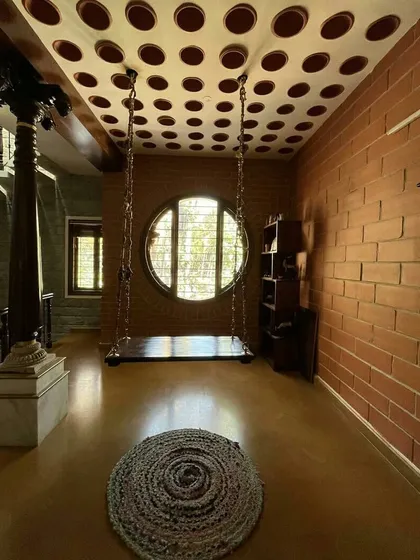 A home should feel spacious and serene, regardless of its size. In this Bangalore residence, an indoor swing, a large circular window, and exposed brick walls come together to create a tranquil corner that is open, airy, and deeply connected to traditional comforts.
