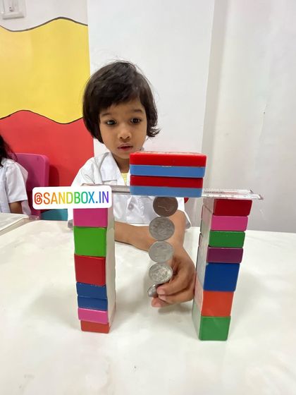 Building and testing magnetic structures helps children develop problem-solving skills. This child is experimenting to see how many coins her creation can hold.